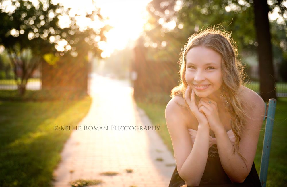 what to expect during senior sessions senior girl with sunlight behind her sitting in chair smiling