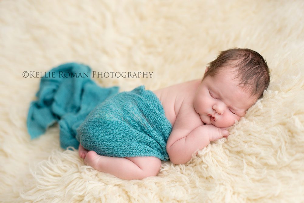 Milwaukee Newborn Photos girl sleeping onto of ivory rug wrapped in teal fabric