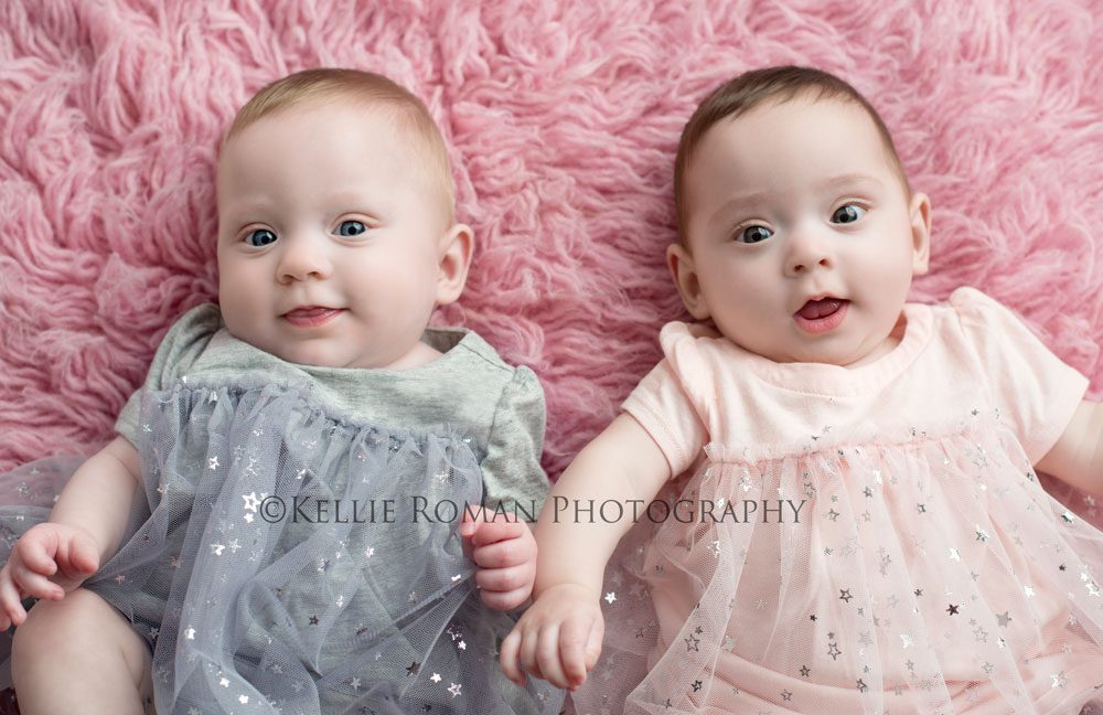Milwaukee Twin Photographer two six month old twins laying on pink rug wearing pink and grey star dresses