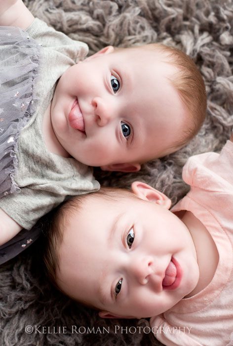 Milwaukee Twin Photographer close up of twin girls looking at camera with their tongues out onto of grey rug