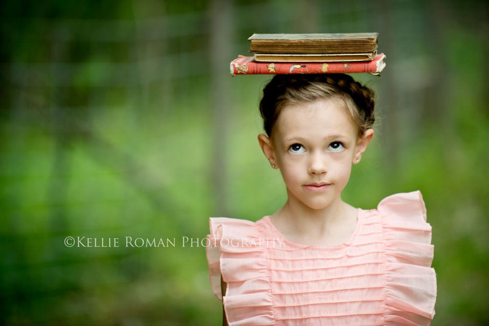 vintage style photo shoot girl with pink dress on balancing books on her head