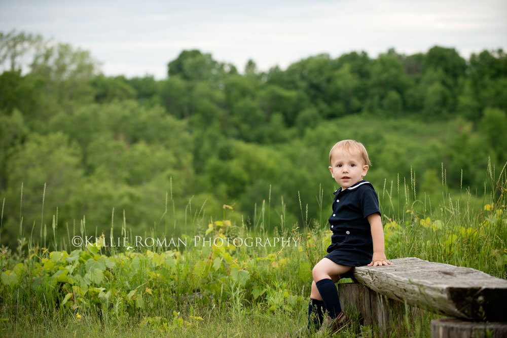 vintage style photo shoot toddler boy wearing sailor outfit sitting on wood bench outside