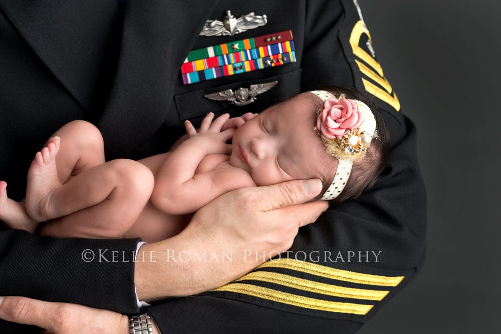 little sailor girl dad wearing naval officer coat holding newborn baby girl with headband on