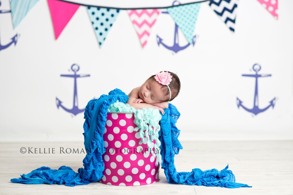 little sailor girl newborn girl posed in polka dot bucket with anchor backdrop colors of blue pink and white