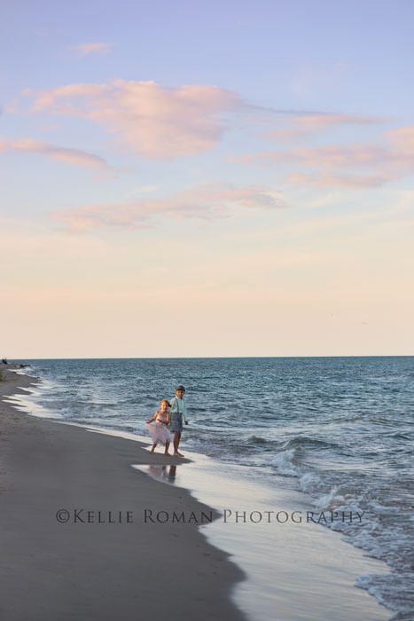 the great lakes two kids running in sand next to water pastel colored sky