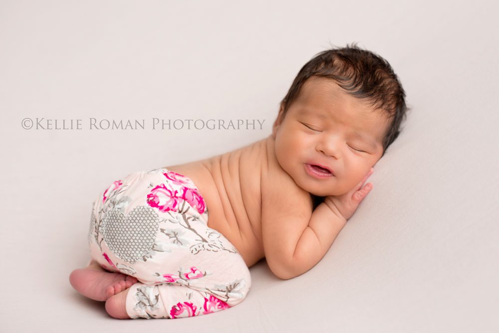 local photographers little infant girl laying on belly onto of light pink blanket wearing pink and grey pants sleeping