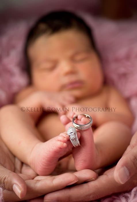 local photographers infant girl with parents wedding rings on toes parents have their hands under the girls feet