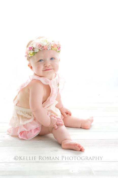 children photography one year old girl with bright backlighting and pink romper and flower headband