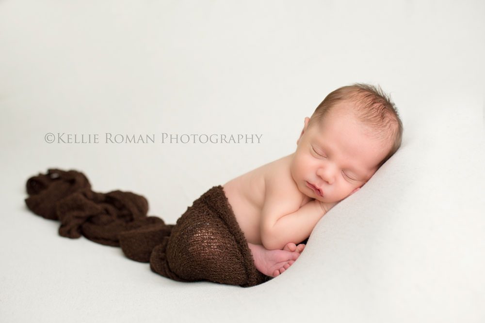 local milwaukee photographers baby boy in taco pose with dark brown wrap on him sleeping on ivory blanket