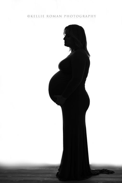 maternity photos a women's silhouette who is pregnant holding on to large baby bump