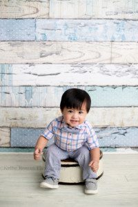 up up and away a one year old boy in Milwaukee studio wearing a plaid shirt and bow tie he's sitting on a white tub looking at the camera