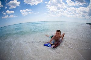 photography session with Kansas Pitts a boy on a boogie board in the gulf coast of Florida smiling in the waves