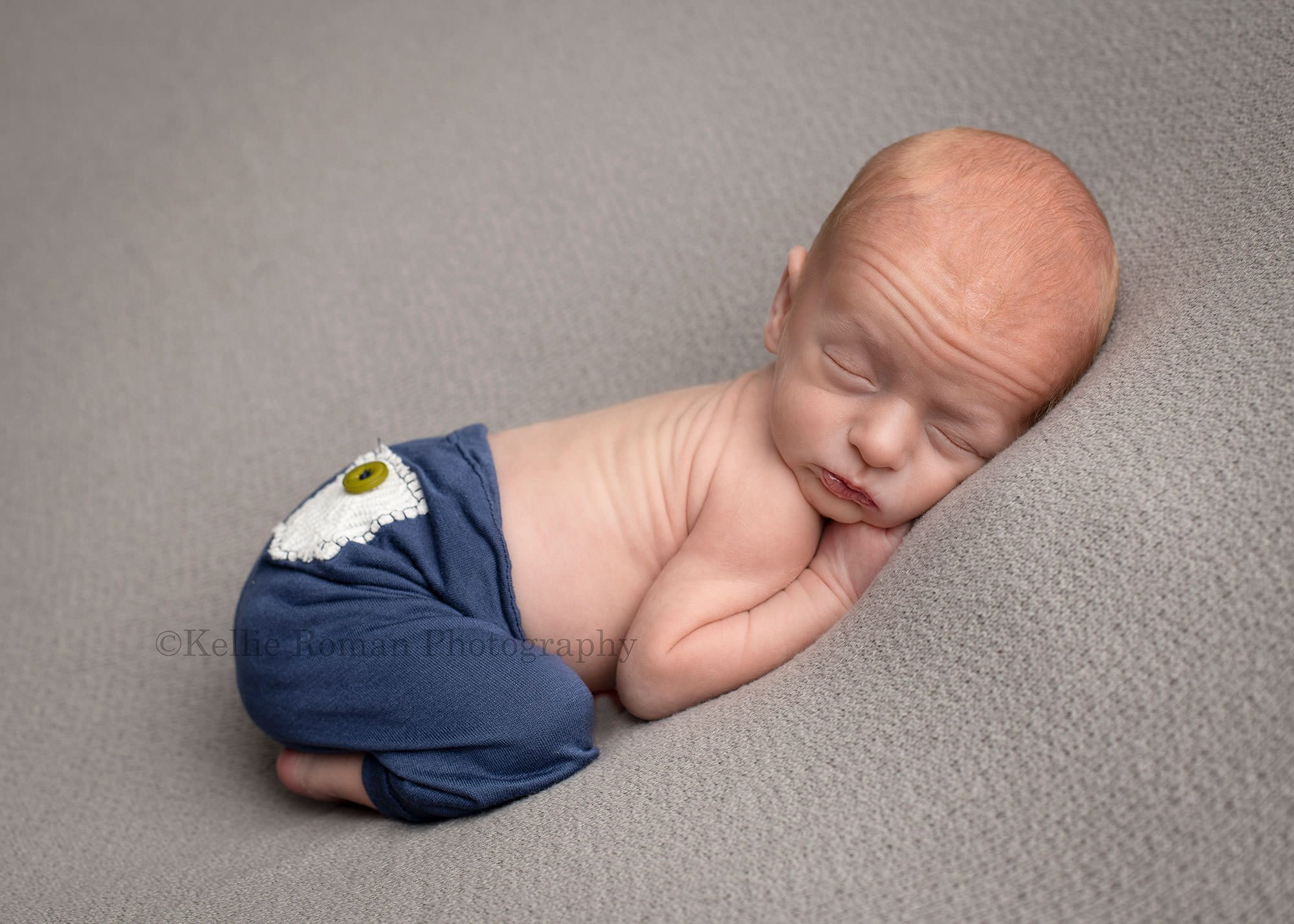 newborn twin pics a newborn boy posed onto of a grey blanket in milwaukee photography studio he has on navy pants and is sleeping