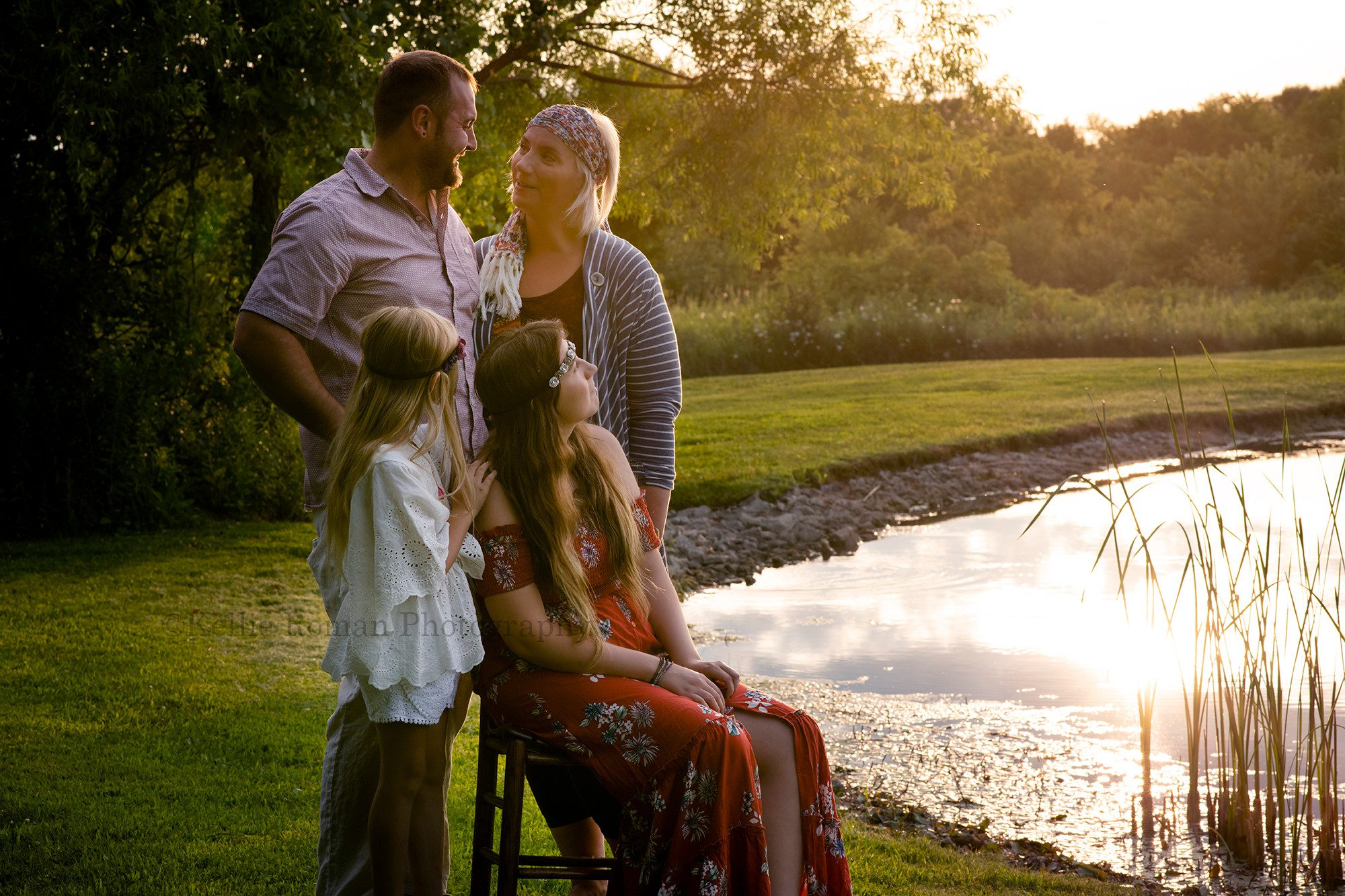 boho inspired a family of four is standing next to a small pond looking at each other they are wearing boho outfits