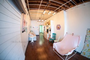 greendale village studio photography studio space in the historic downtown greendale village in milwaukee county Wisconsin image shows the main studio area with backdrops on the wall a newborn posing area a parent lounge with a tv and couch colors are all pastel with white walls