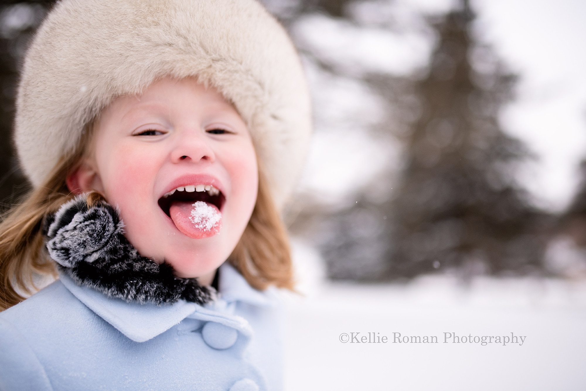 milwaukee snowfall a 5 year old girl is outside in the snow in a Milwaukee County park she's wearing a baby blue pea coat from Scotland and a black fur scarf and a white fur hat from Russia. She is looking at the camera and sticking her tongue out with snow on her tongue.