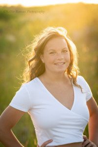 milwaukee senior pics a young teenage girl is outdoors in a Milwaukee County park. the sunset is shining from behind her and there is lots of golden sunflair on her. she's wearing a white shirt and has her hands on her hips