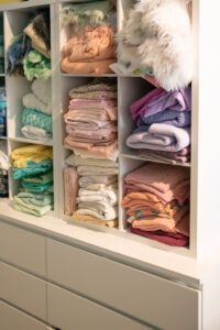New Milwaukee Photography Studio. An image of a white cube cabinet holding several organized color coded fabrics and furs. This is inside of a Bayview Photographer's Studio.