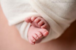 little newborn changes. a close up image of a newborn girls toes. they are pink and they are resting on a light pink fabric.