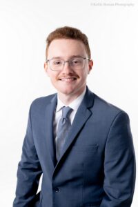 milwaukee headshot photographer. close up image of a man with glasses and a suit and tie on. he's in front of a white backdrop.