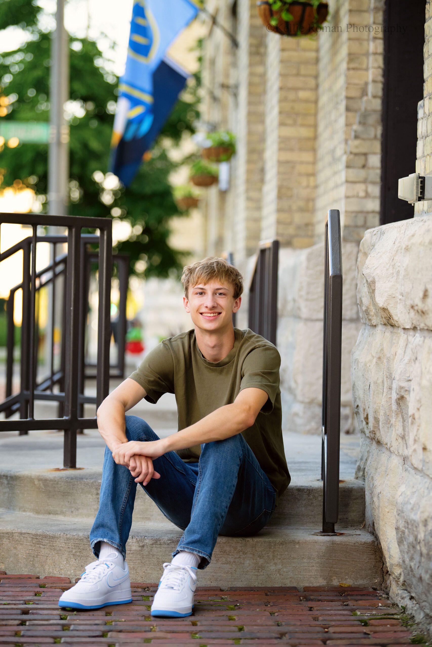 milwaukee senior pictures. oak creek high school senior sitting on stairs in downtown milwaukee. he has a green shirt on with jeans.